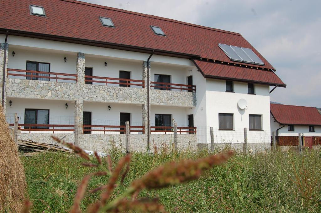 een wit gebouw met een rood dak bij Pensiunea Bogdan in Novaci-Străini