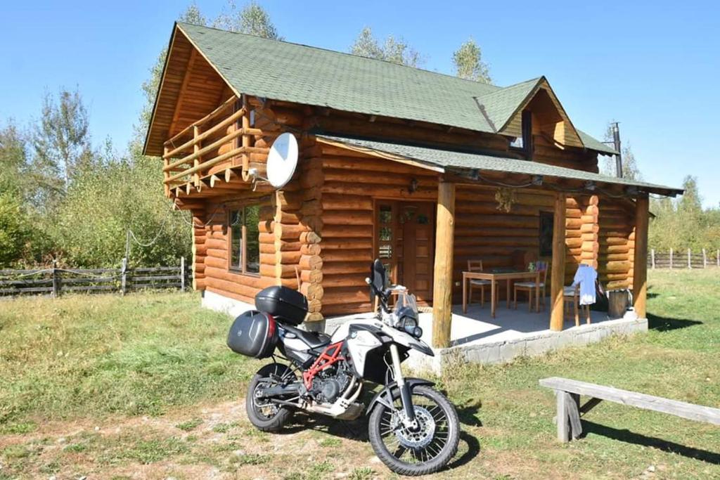 a motorcycle parked in front of a log cabin at Musketeers Cabin in Porumbacu de Sus