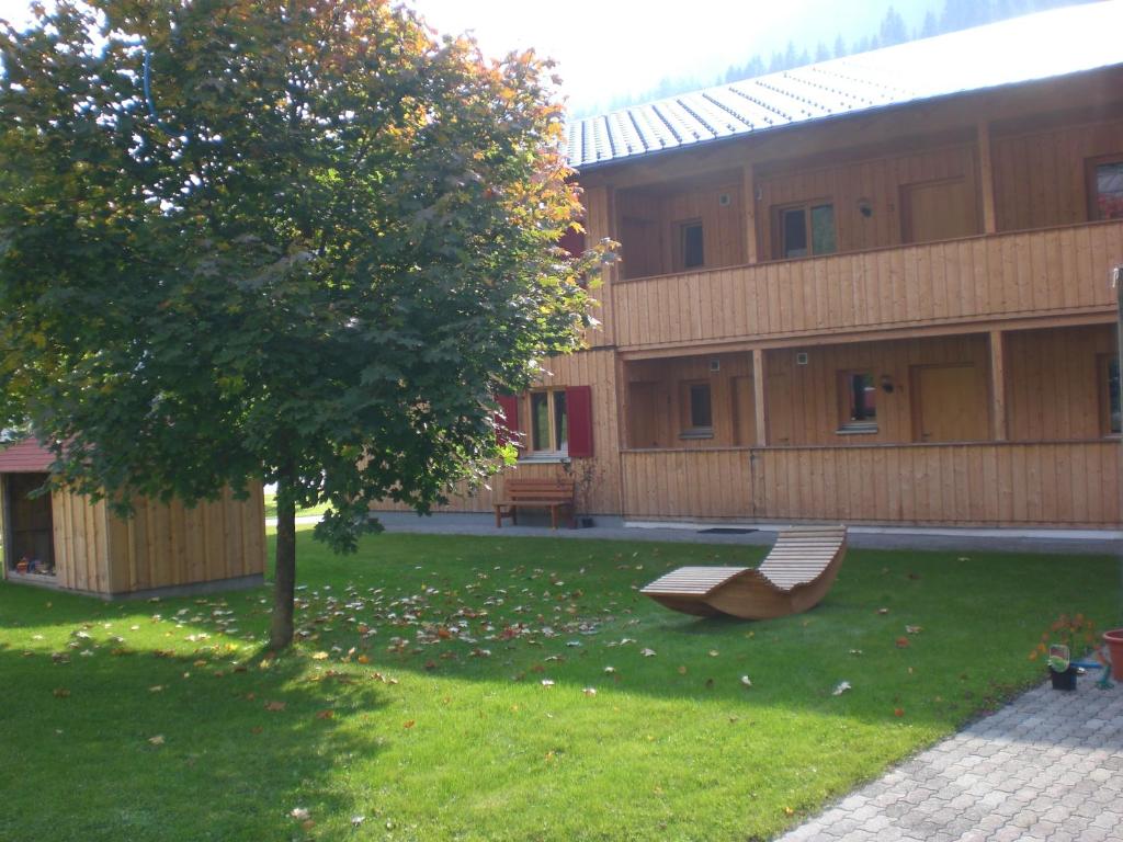 a green yard with a bench in front of a building at Gästehaus zum Bären in Wald am Arlberg