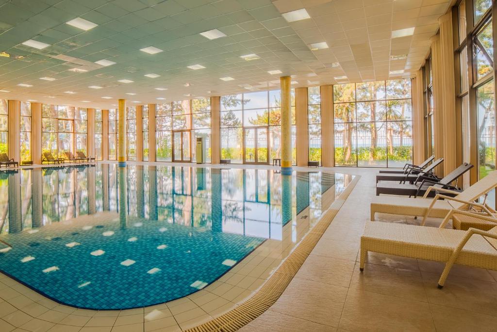 a large swimming pool in a building with windows at Kobuleti Georgia Palace Hotel & Spa in Kobuleti