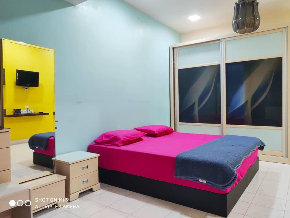 HOMESTAY GOMBAK PERMAI في بانيا إليجا: غرفة نوم مع سرير وردي كبير وتلفزيون