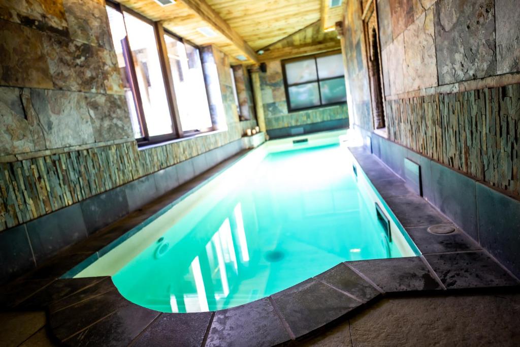 an indoor swimming pool in a building with windows at Hotel et Spa Le Lion d'Or in Pont-lʼÉvêque