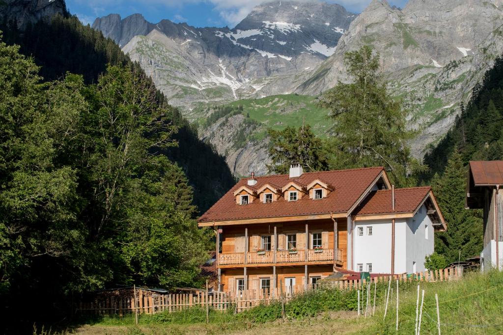 a house on a hill with mountains in the background at Riversong Centre Thermal in Les Plans-sur-Bex