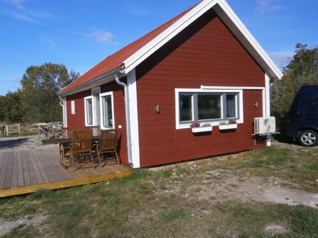 a red house with a deck next to a van at Stuga på Hasslö in Bredavik