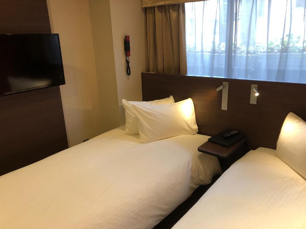 ein Hotelzimmer mit 2 Betten und einem Flachbild-TV in der Unterkunft Red Roof Inn Kamata / Haneda Tokyo in Tokio