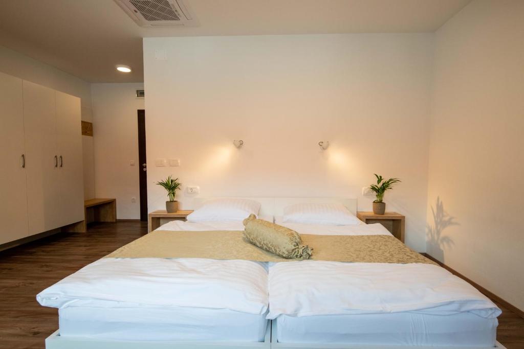 una camera con 2 letti con lenzuola e cuscini bianchi di Guesthouse Stari Mayr a Kranj