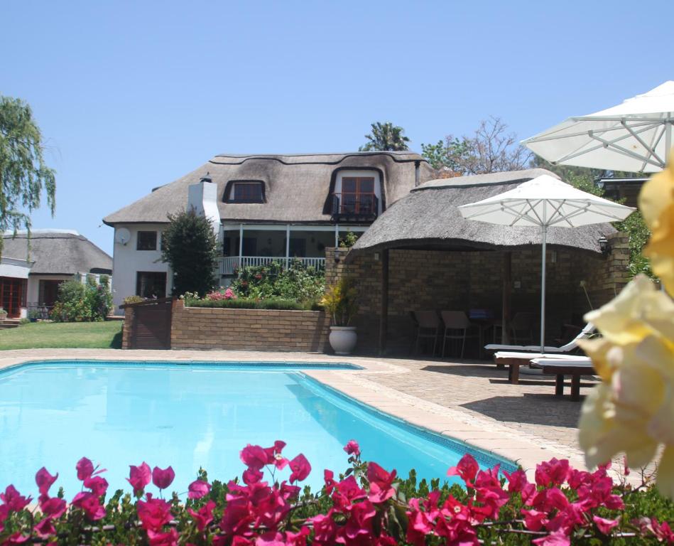 a house with a swimming pool and pink flowers at Acara Guest Cottages in Stellenbosch