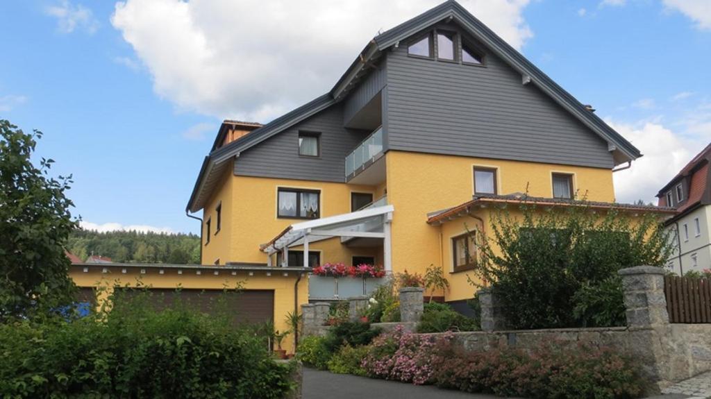 een geel huis met een grijs dak bij Pension Leppert in Bischofsgrün
