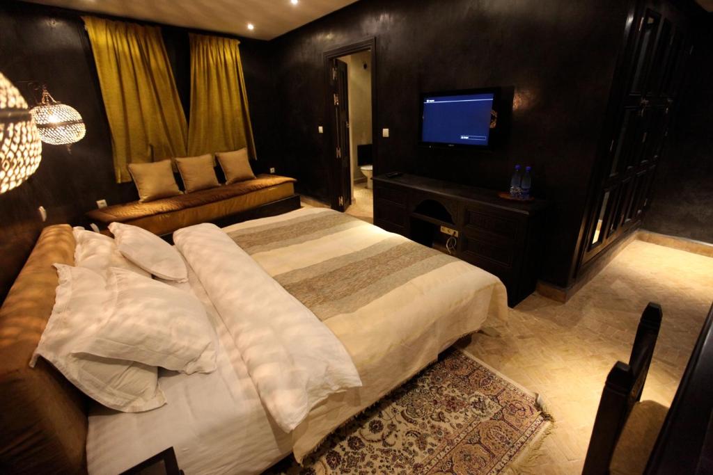 a bedroom with a large bed and a flat screen tv at Riad Dar Haven in Tamraght Ou Fella