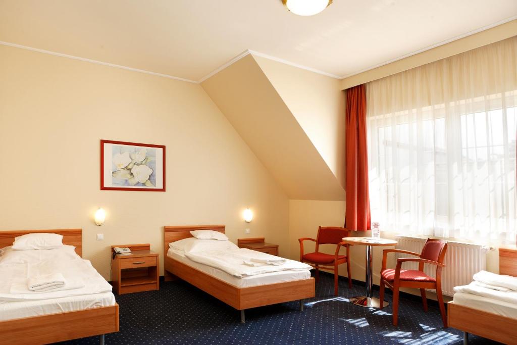 a hotel room with two beds and a window at Hotel Paprika in Hegyeshalom