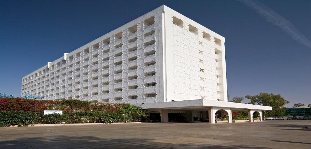 een groot wit gebouw met een parkeerplaats ervoor bij Clarks Amer in Jaipur