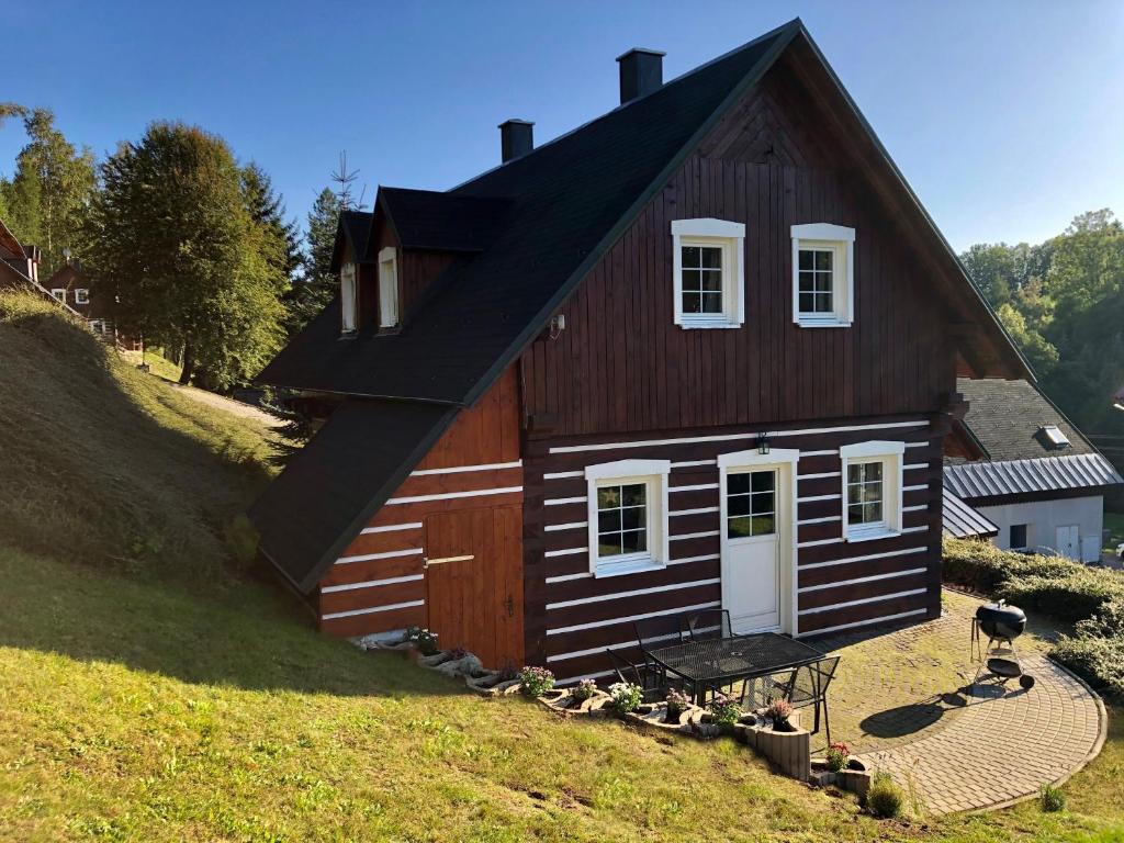 a small house with a black roof on a hill at Modern chalet Na Zlatníku in Zlatá Olešnice