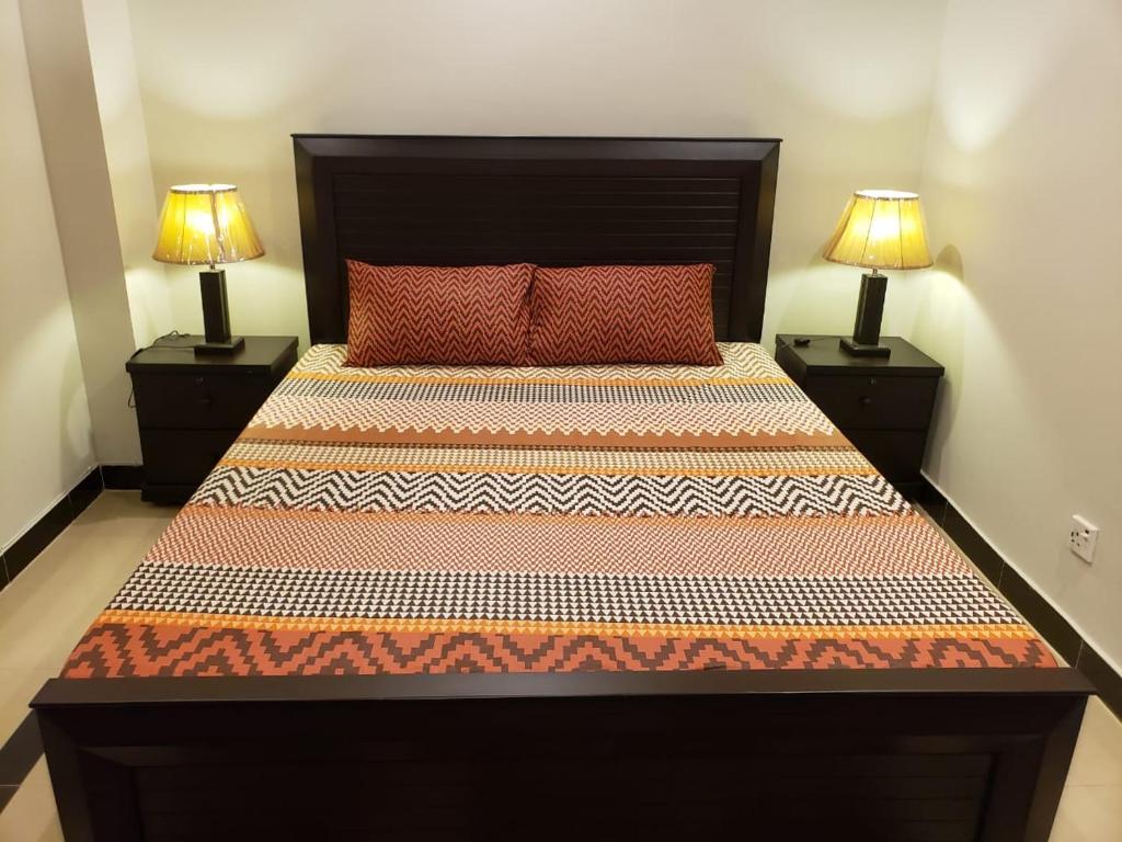 a bedroom with a large bed with two lamps at Rove Lodging-One Bed Apartment,Bahria Town in Rawalpindi