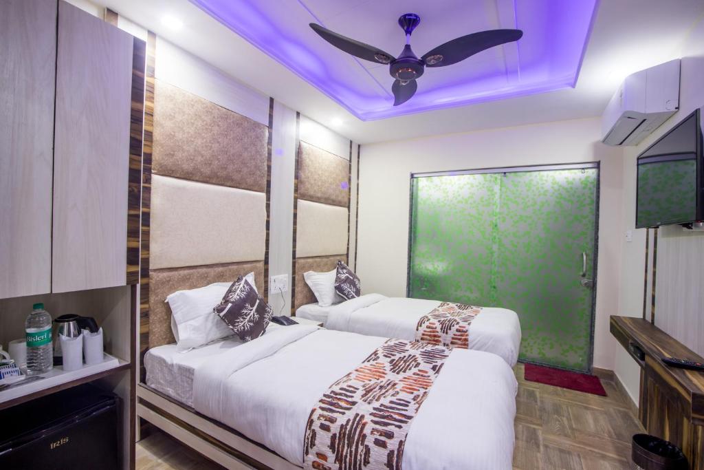 2 bedden in een kamer met een plafondventilator bij Hotel Harsha International in New Delhi
