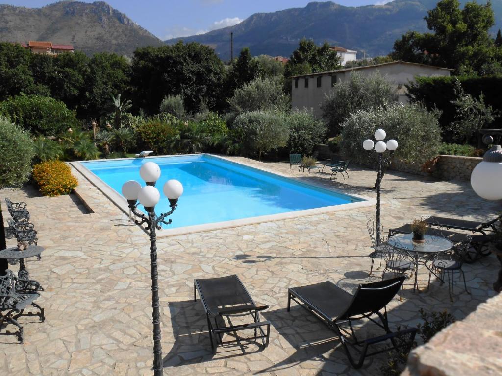 una piscina con sillas, una mesa y un patio en B&B Al Giardino, en Monreale