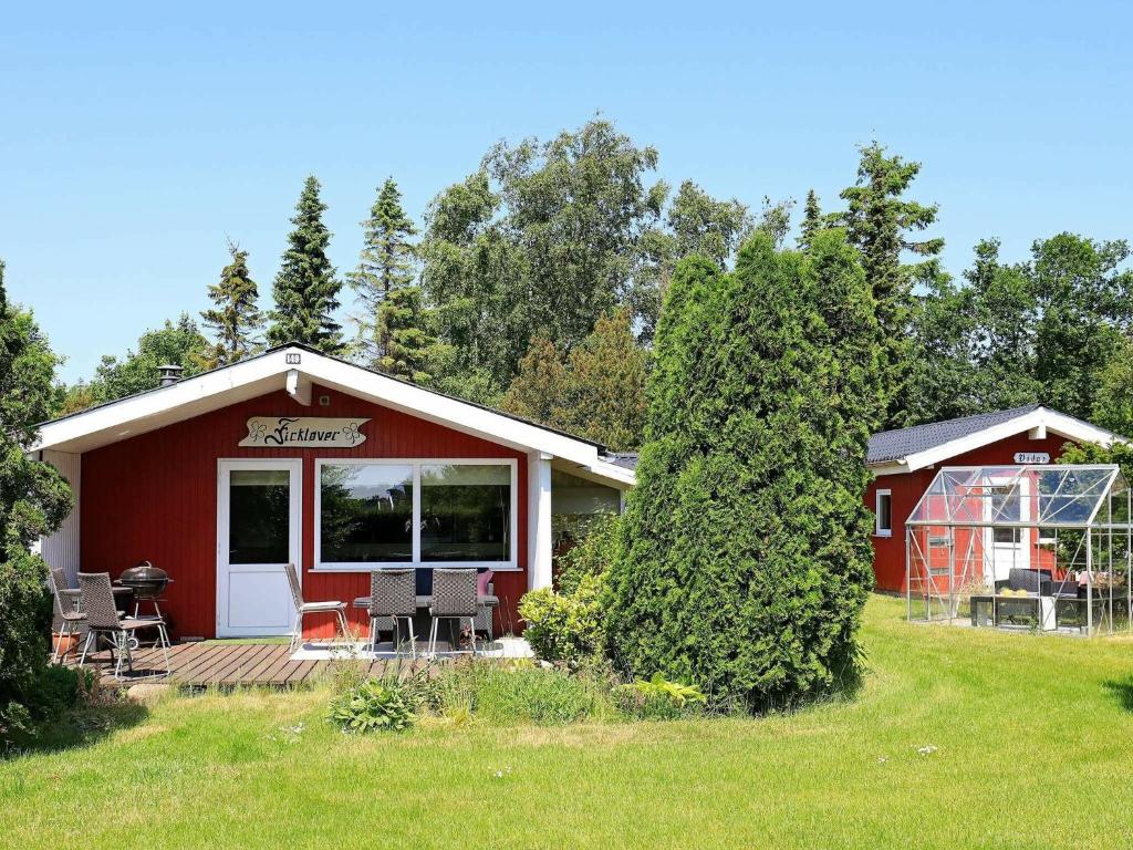 a red cabin with a deck and chairs in a yard at Holiday home Frederikshavn II in Frederikshavn