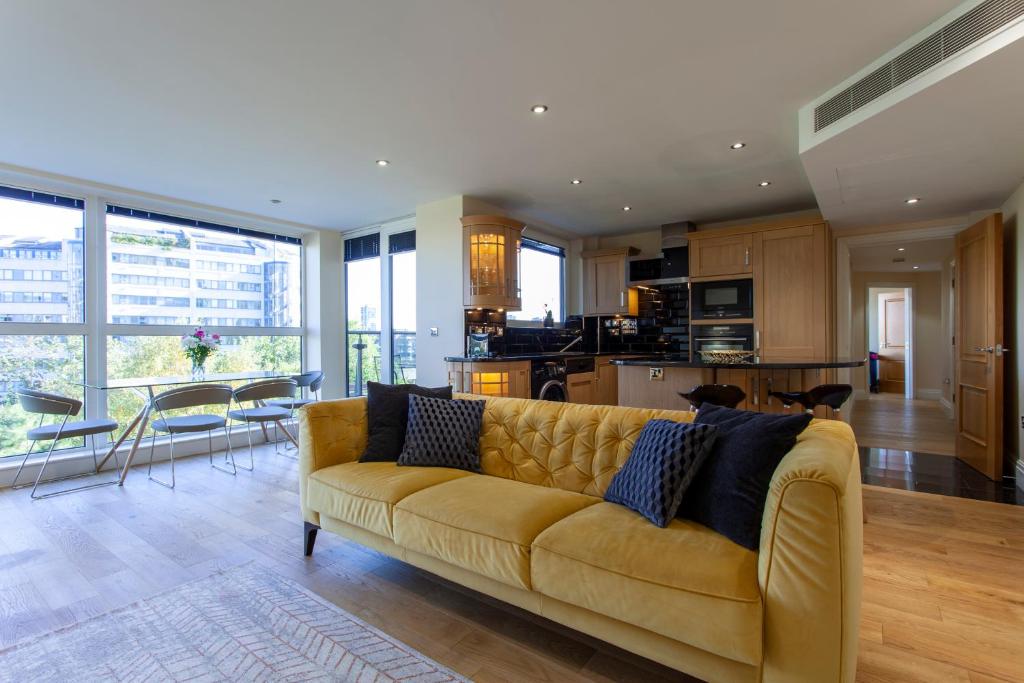 a living room with a yellow couch and a kitchen at Thames View Apartment, Imperial Wharf in London