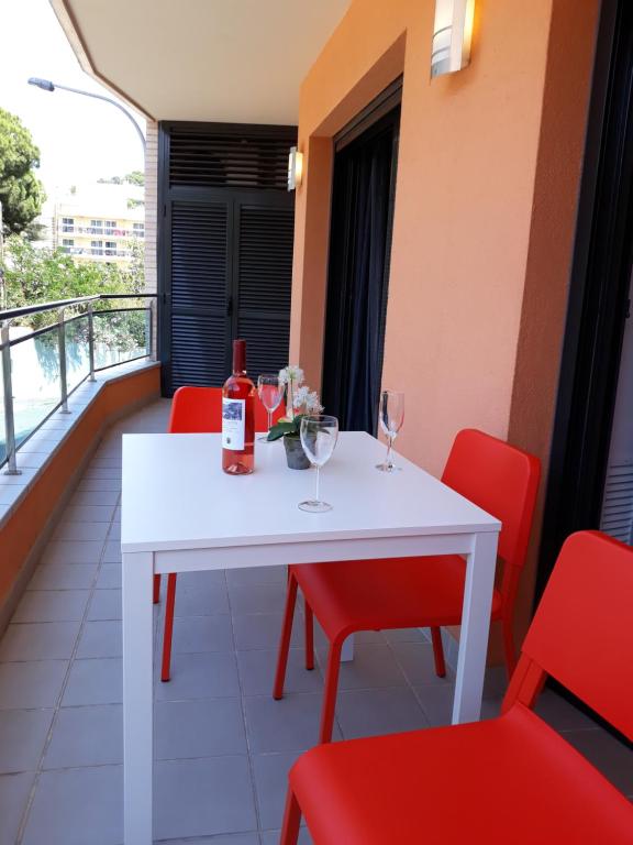 リョレート・デ・マルにあるApartment Iliaの白いテーブル(ワイングラス付)、バルコニー(赤い椅子付)