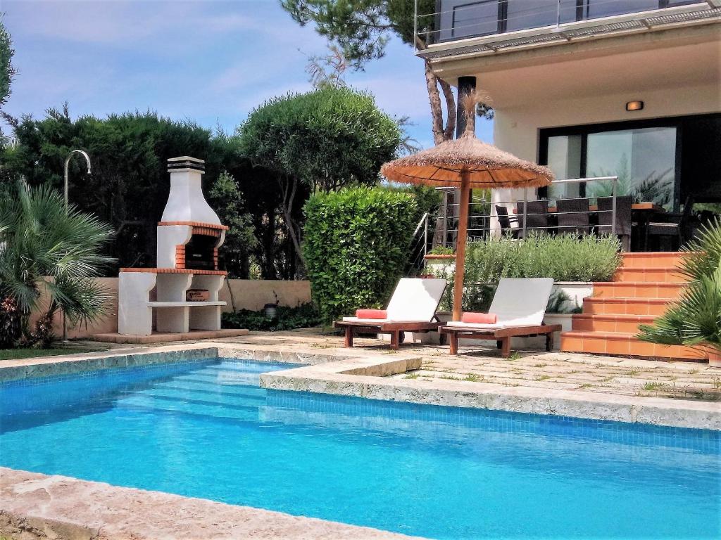 una piscina con due sedie e un ombrellone accanto a una casa di Es Baulo Pleta a Can Picafort