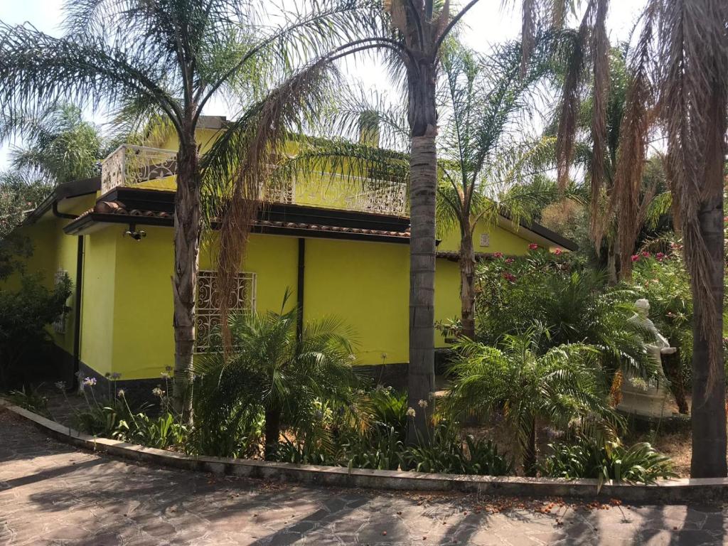 une maison jaune avec des palmiers devant elle dans l'établissement Villa Romana, à Ricadi