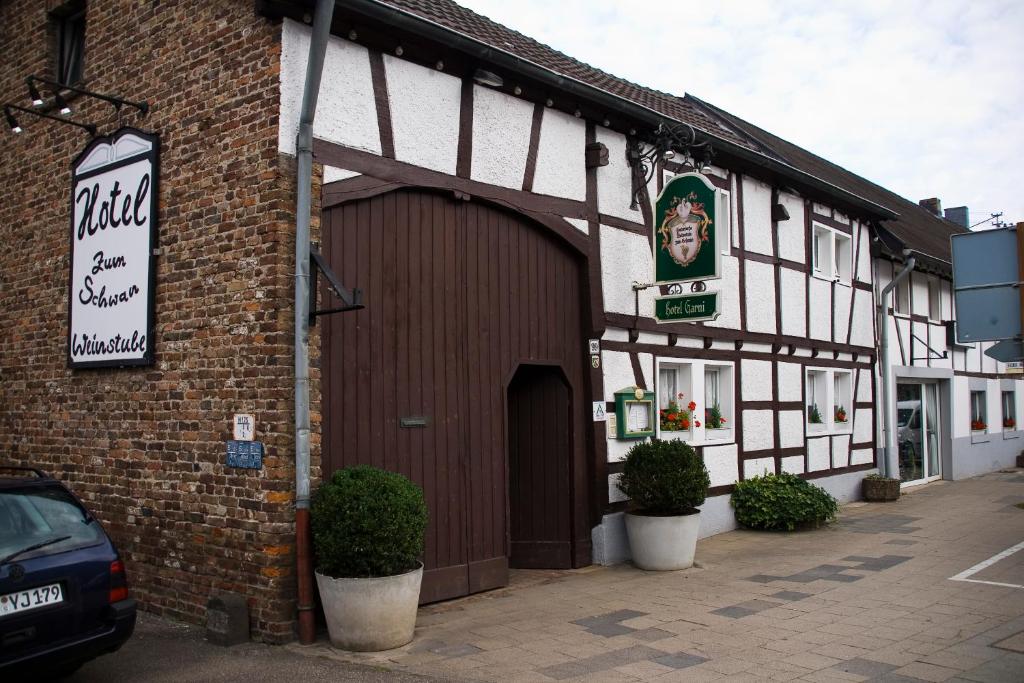 un edificio con garage con auto parcheggiata fuori di Hotel zum Schwan Weilerswist a Weilerswist