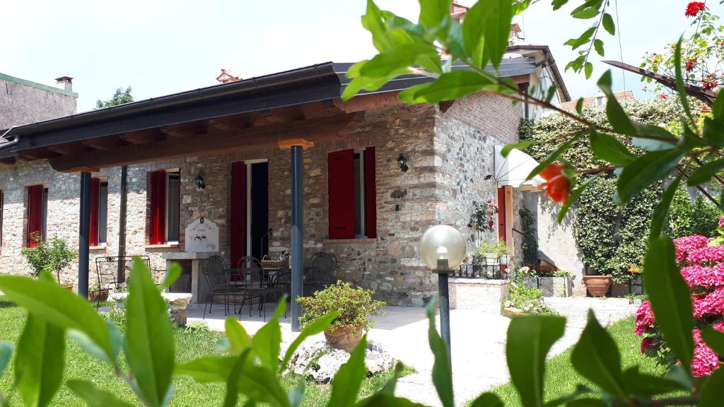 a stone house with red shutters and a garden at le scuderie di s.Bakhita in Schio