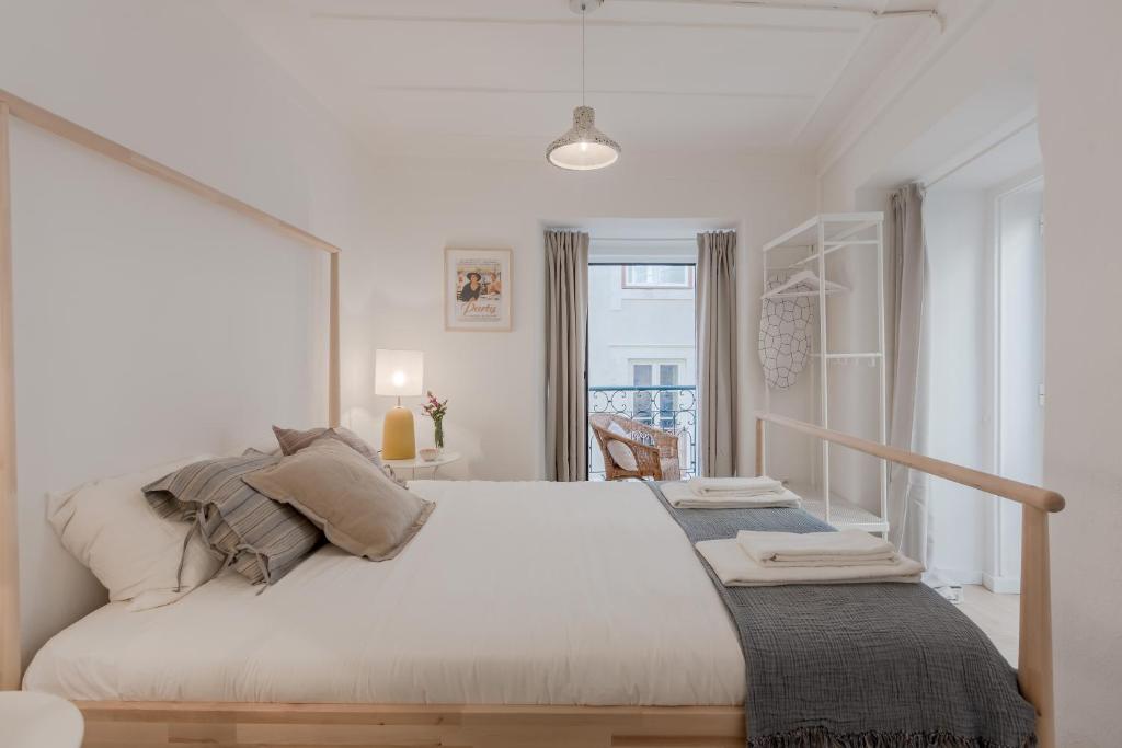 biała sypialnia z dużym łóżkiem i oknem w obiekcie Sunny Bairro Alto & Chiado Apartment, By TimeCooler w Lizbonie