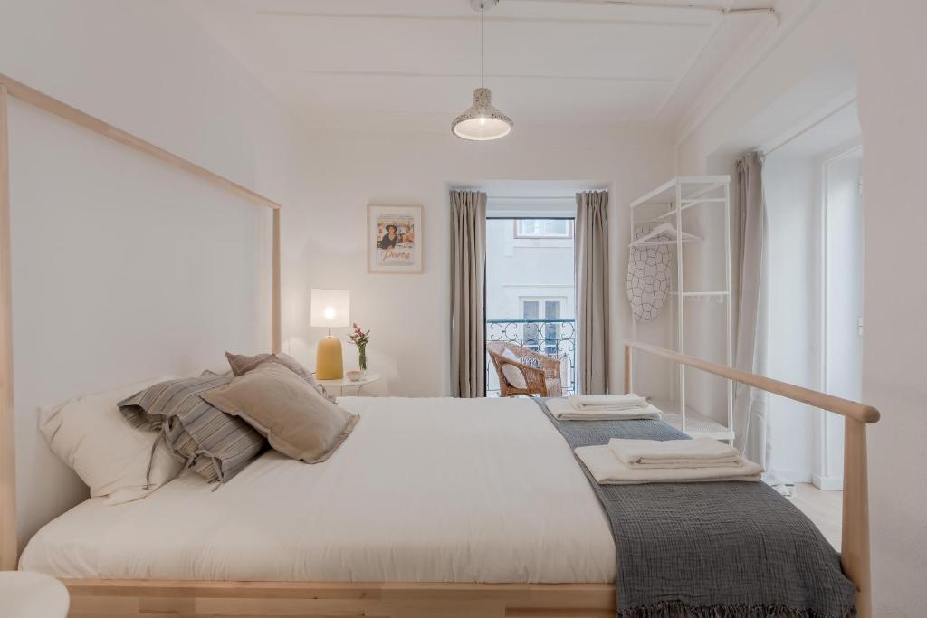 a white bedroom with a large bed and a window at Sunny Bairro Alto & Chiado Apartment, By TimeCooler in Lisbon