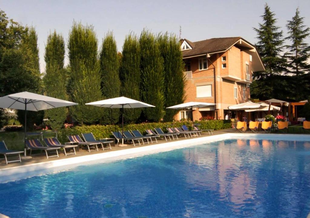 una gran piscina con sillas y sombrillas en Il Cascinalenuovo, en Asti