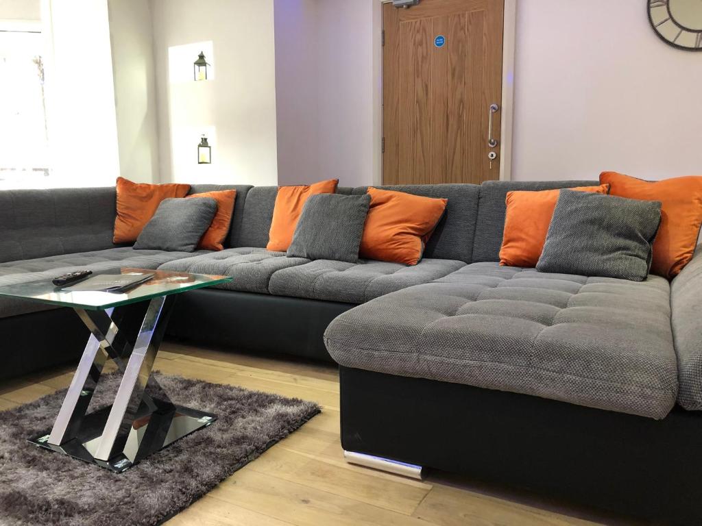 ein Wohnzimmer mit einem grauen Sofa und orangefarbenen Kissen in der Unterkunft Princess Theatre Beach View Apartments in Blackpool
