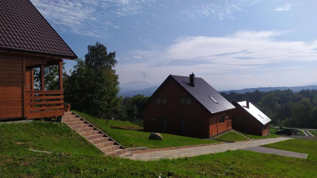 un par de graneros en una colina al lado de una casa en Domki w Beskidach en Zarzecze