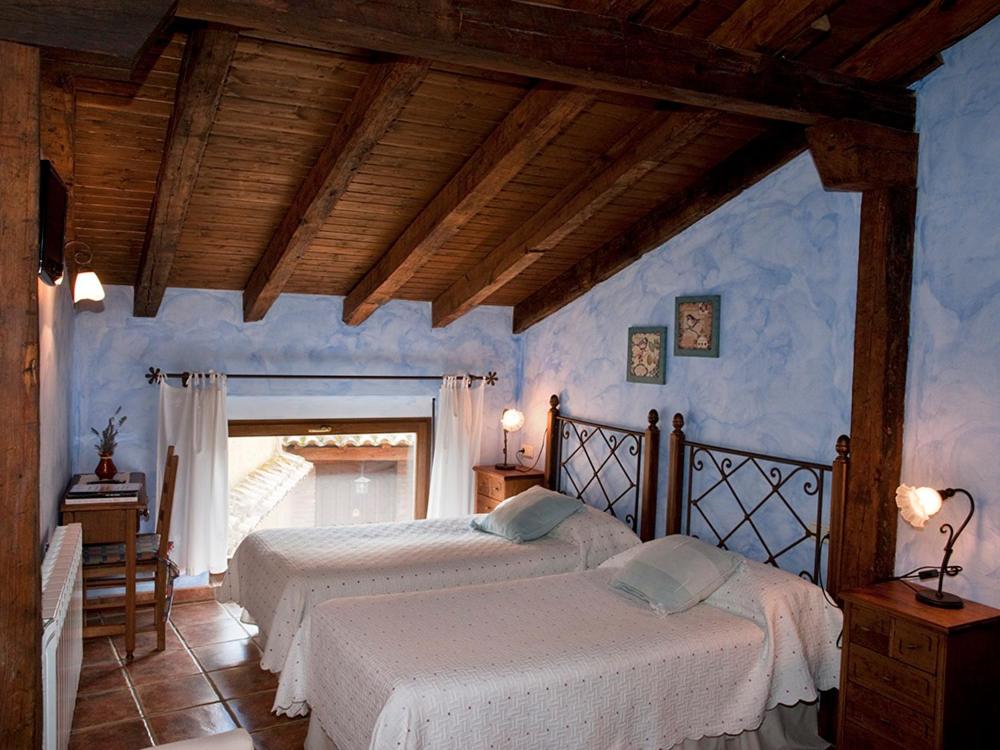 2 camas en un dormitorio con paredes azules en Casa Rural El Encuentro, en Villalón de Campos