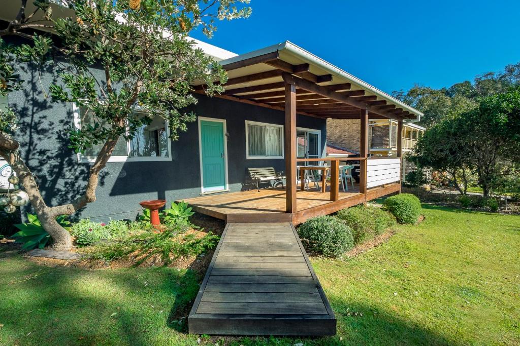 a house with a wooden porch with a deck at Tallowood beachfront cottage in Bonny Hills