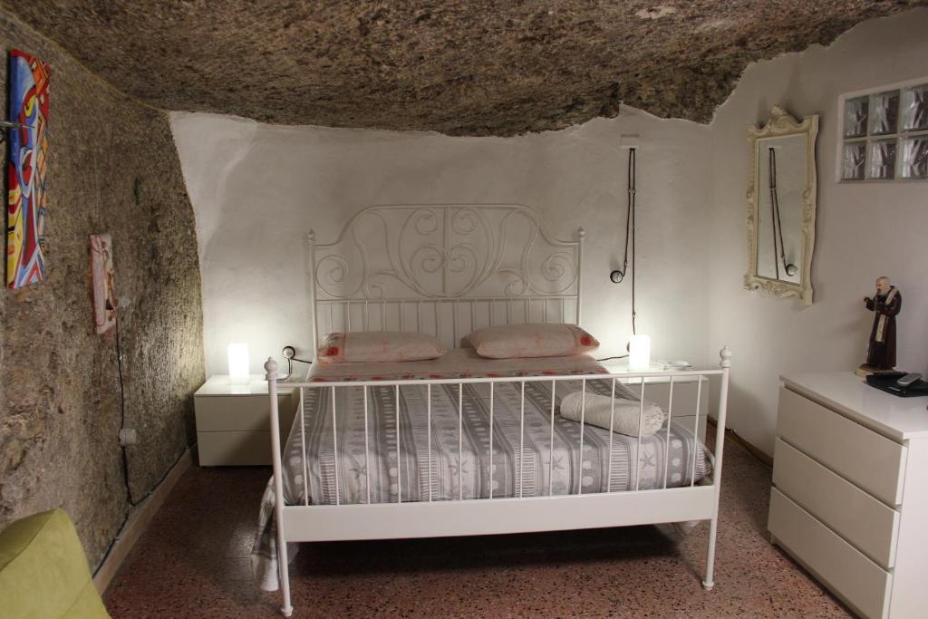 a bedroom with a white bed in a stone wall at Camera Nella Roccia in Tropea