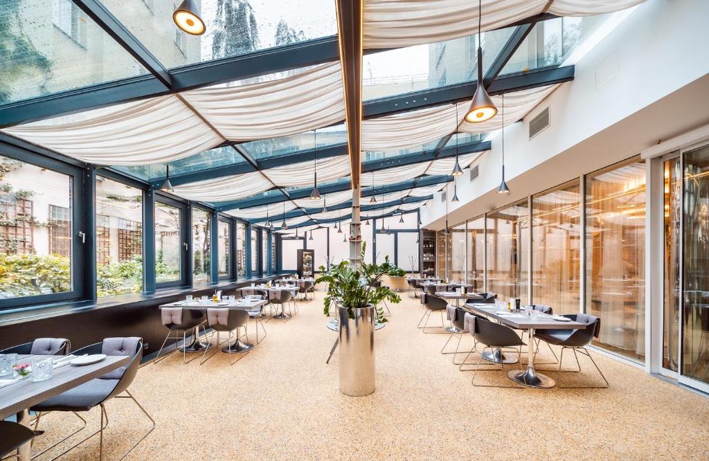 restauracja ze stołami, krzesłami i oknami w obiekcie Grandium Hotel Prague w Pradze