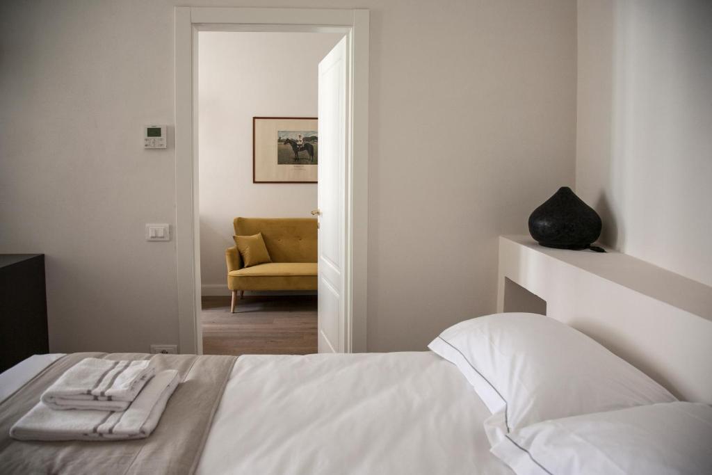 1 dormitorio con cama blanca y sofá amarillo en Pietrapiana34 Boutique Apartments, en Florencia