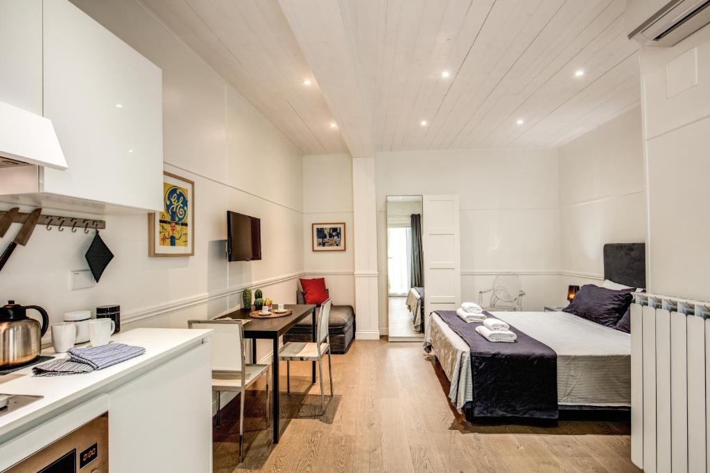 ローマにあるColosseo Suite Apartmentのベッド1台付きの部屋、テーブル付きのキッチンが備わる客室です。
