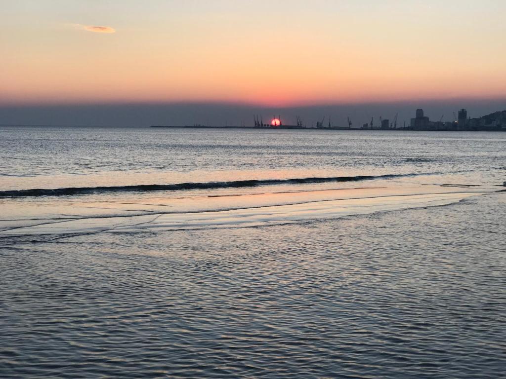 a sunset on the beach with a city in the background at Beach Apartaments in Durrës