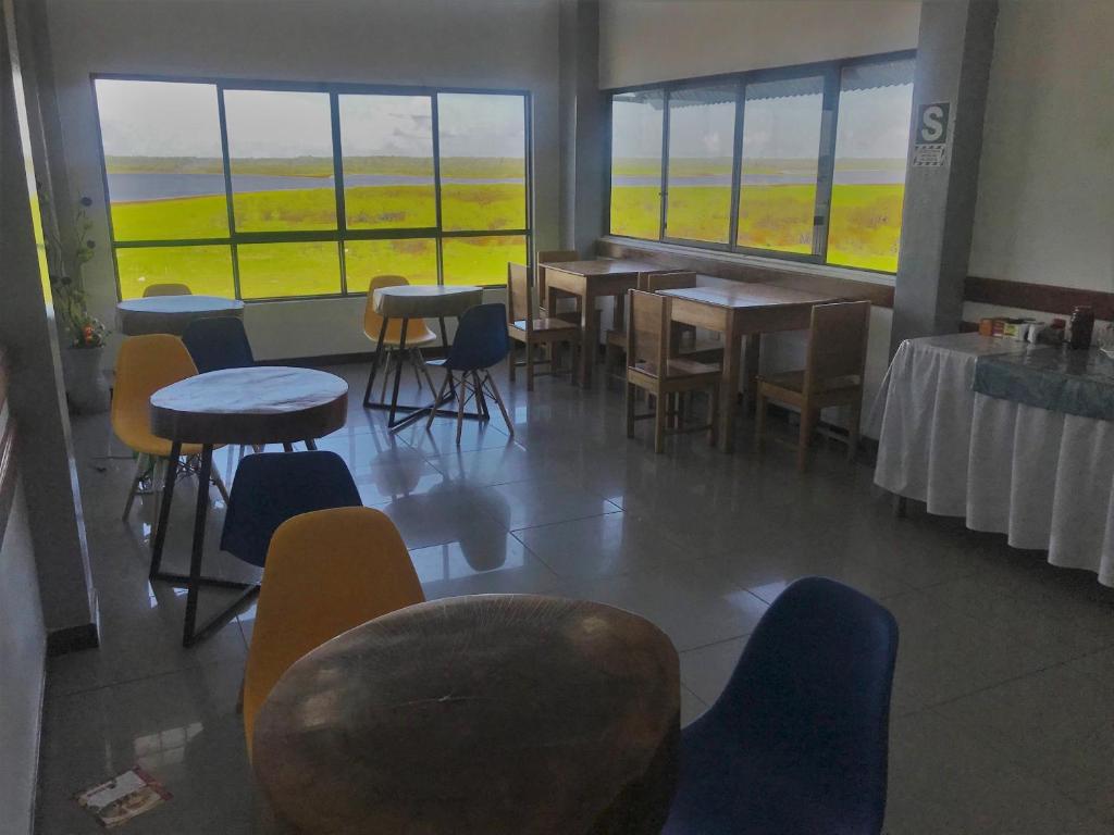 a dining room with tables and chairs and windows at Amazon Dream Hostel with AC and Starlink in Iquitos