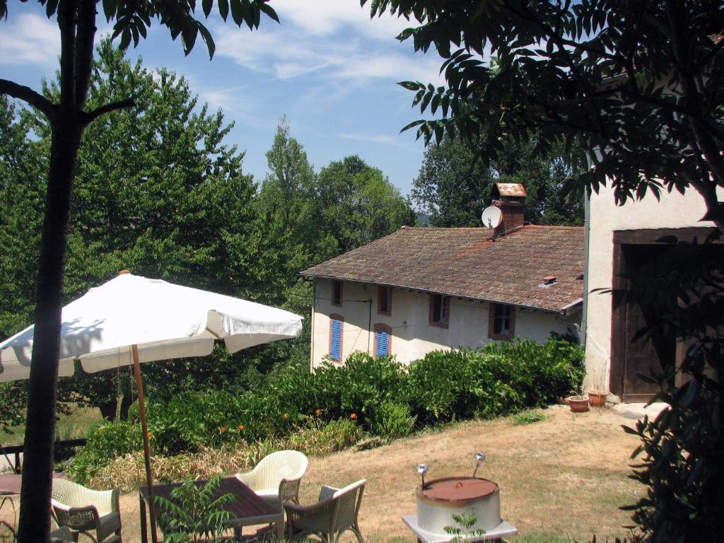 Camping La Vallée Verte في أمبيرت: منزل فيه مظله وطاولة وكراسي