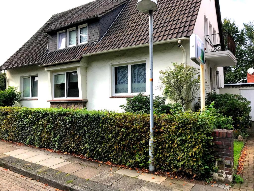 a house with a street light in front of a hedge at Rustic Overnight Apartment in Osterholz-Scharmbeck