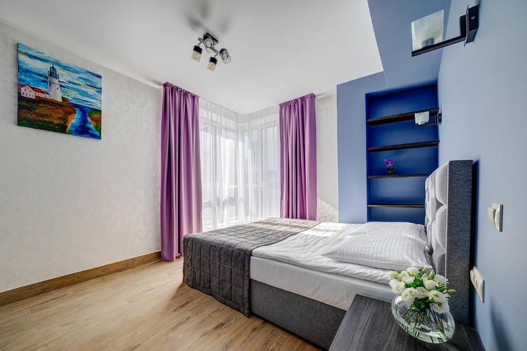1 dormitorio con 1 cama y una ventana con cortinas moradas en Hotel Luidor, en Tver