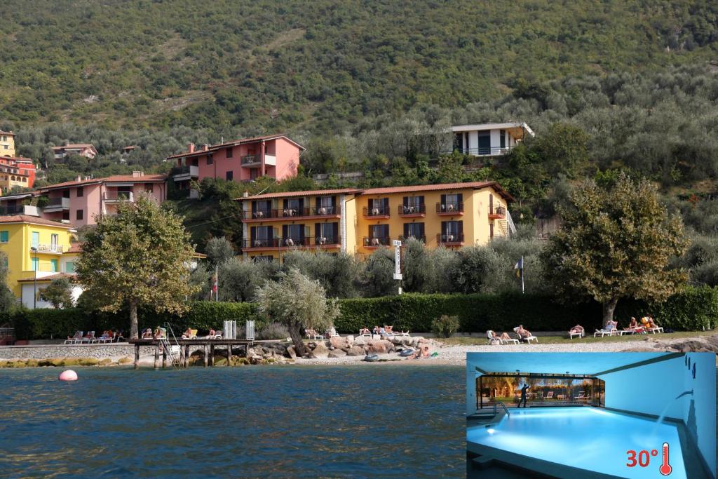 un bateau sur l'eau avec des bâtiments en arrière-plan dans l'établissement Hotel Rabay, à Brenzone