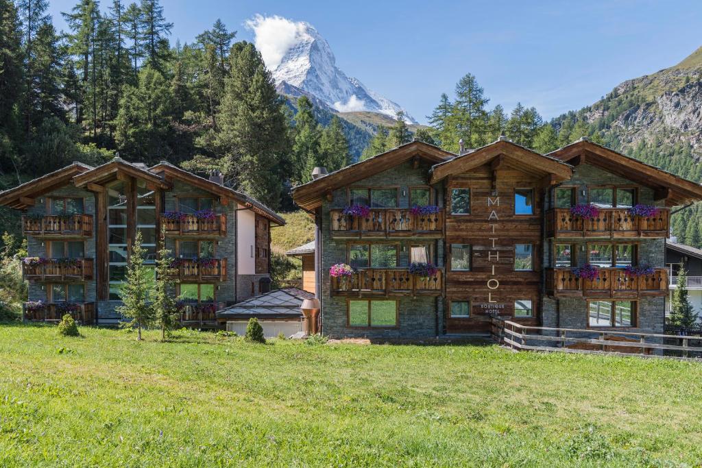 um grande edifício de madeira com uma montanha ao fundo em Matthiol Boutique Hotel em Zermatt