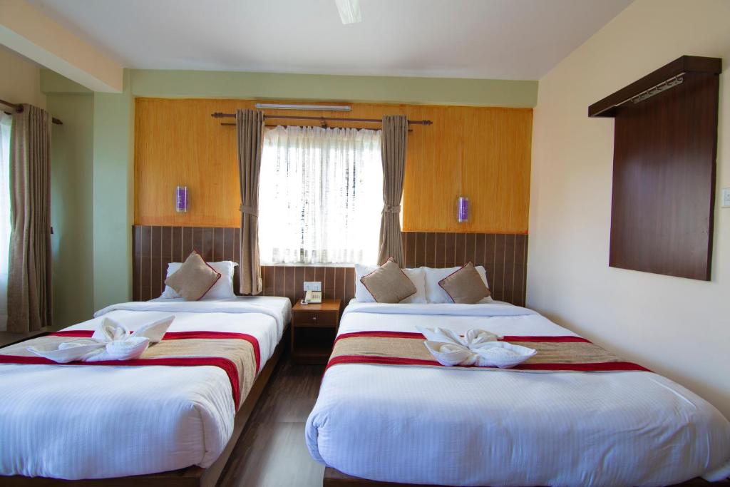 una camera d'albergo con due letti e una finestra di Hotel Guru a Pokhara