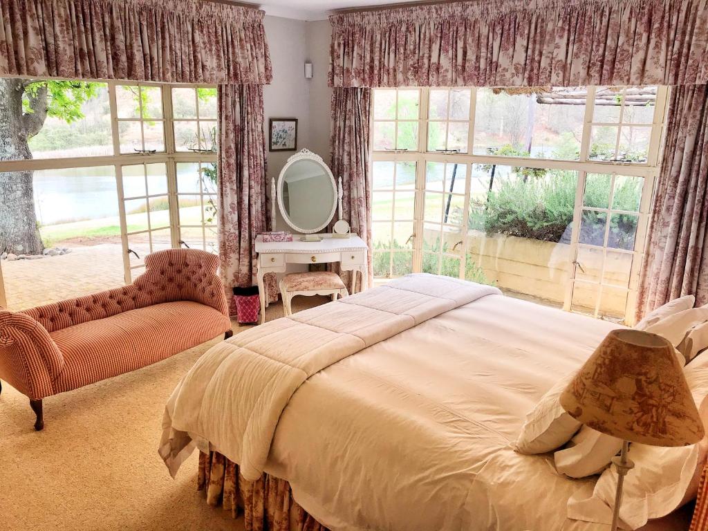 ein Schlafzimmer mit einem Bett, einem Spiegel und einem Stuhl in der Unterkunft Rose Cottage @ Gods' Haven Eco Estate in Underberg
