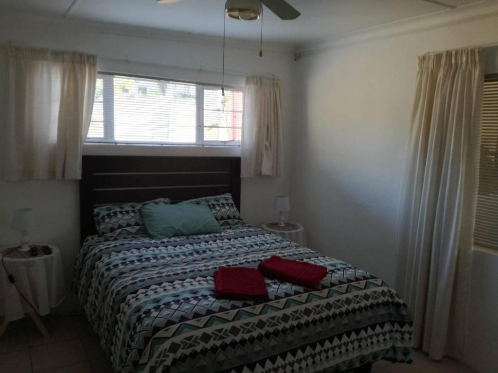 東倫敦的住宿－Hunters Self Catering Apartment，一间卧室配有一张带两个红色枕头的床