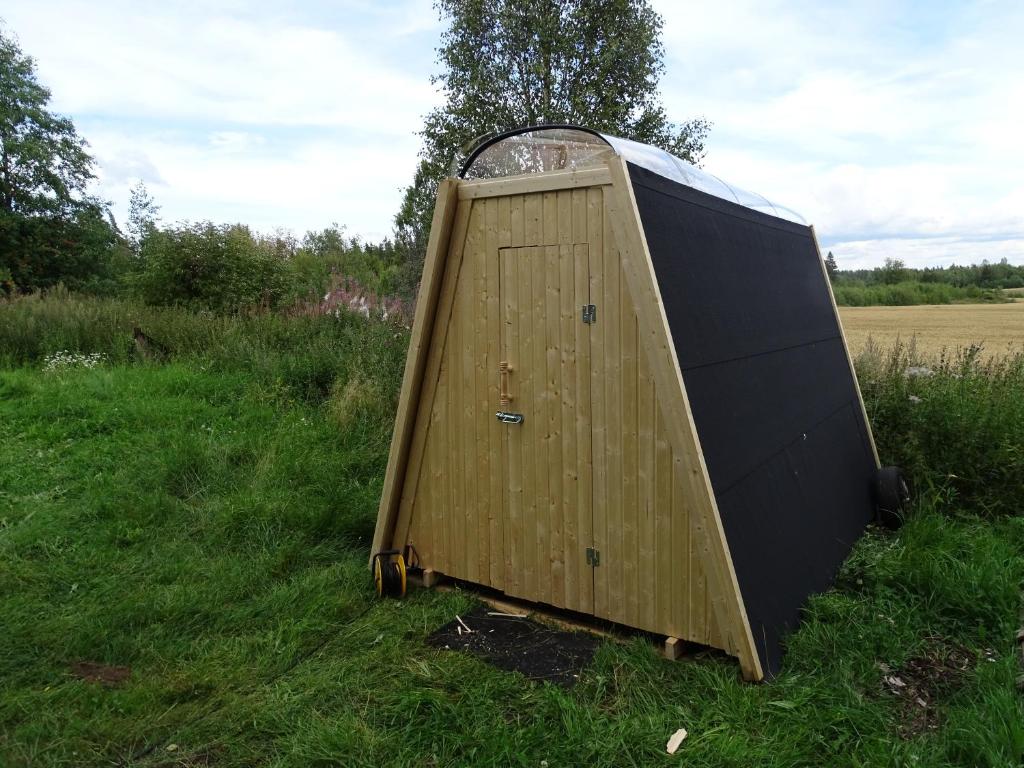 a large wooden object sitting in the grass at Niiralan Tila: Skylight Cabin in Laitila