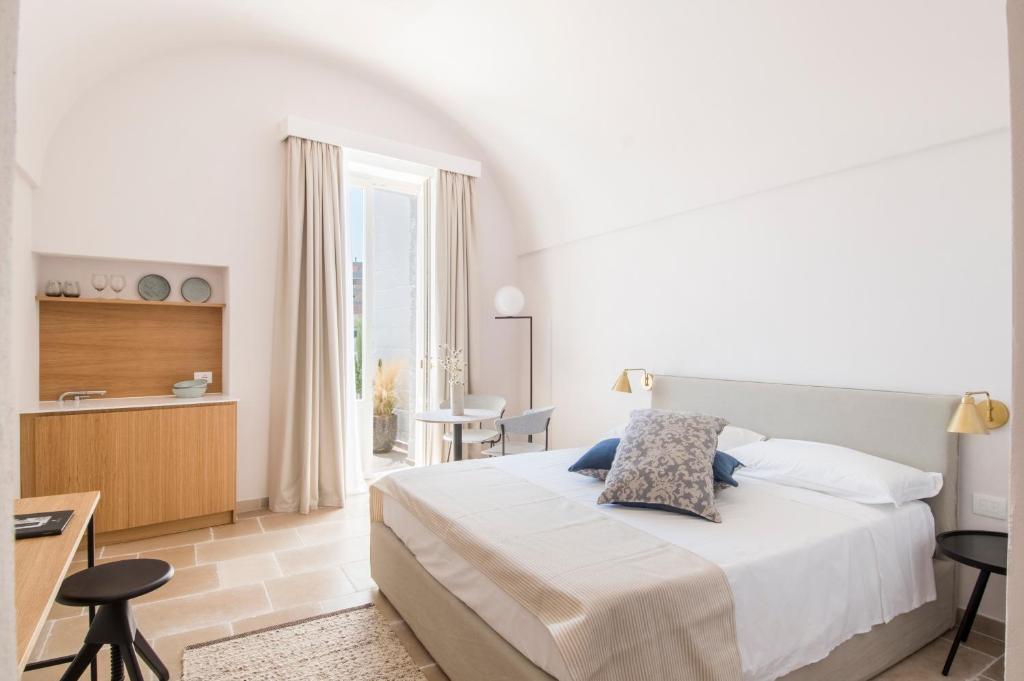 a white bedroom with a bed and a desk and a window at Palazzo Mulini in Monopoli