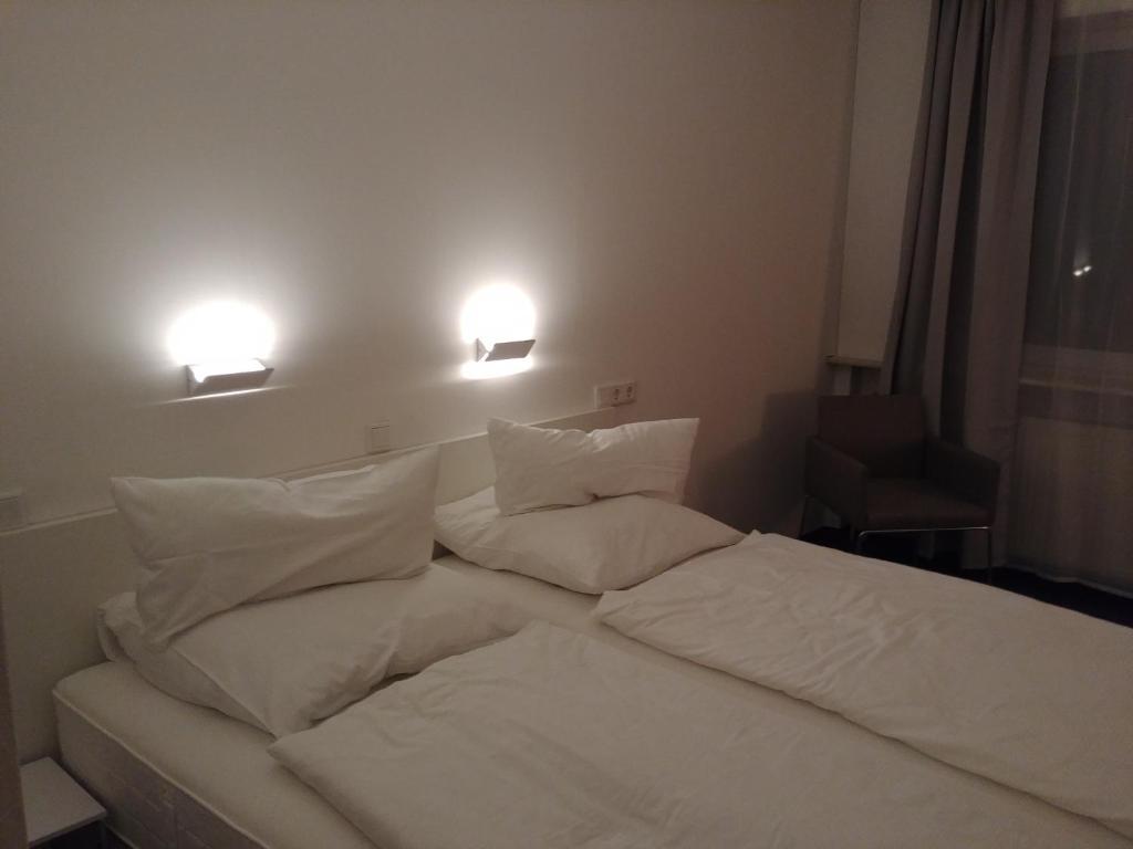 Bett mit weißer Bettwäsche und Kissen in einem Zimmer in der Unterkunft Hotel Panorama in Niederfüllbach